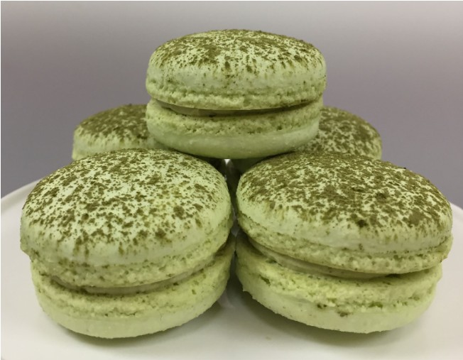macarons A small plastic measuring spoon on its side with a pile of vibrant spirulina powder against a white background